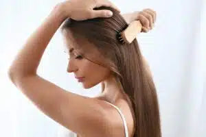 Woman brushing her long hair against a plain background
